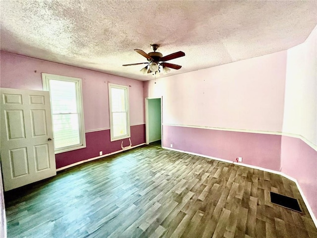 unfurnished room with wood finished floors, a textured ceiling, a ceiling fan, and baseboards