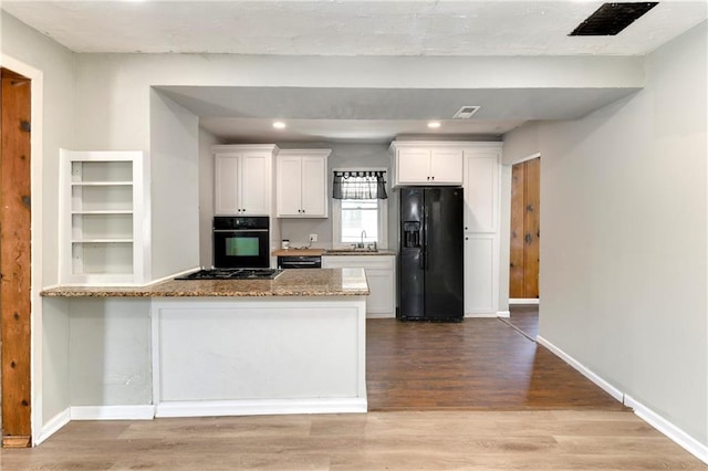 2409 Oakley Ave, Kansas City, MO 64127 - kitchen with black appliances, a sink, white cabinets, light stone countertops, and wood finished floors