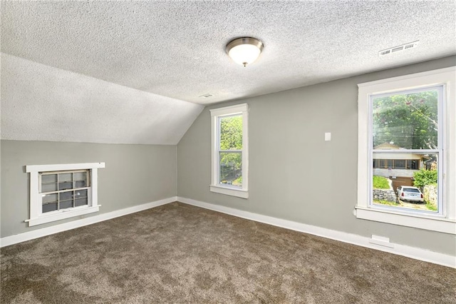 2409 Oakley Ave, Kansas City, MO 64127 - additional living space featuring dark colored carpet, a textured ceiling, baseboards, and lofted ceiling