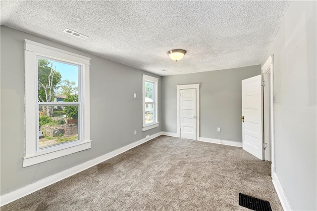 2409 Oakley Ave, Kansas City, MO 64127 - unfurnished bedroom featuring multiple windows, carpet flooring, a textured ceiling, baseboards, and a closet