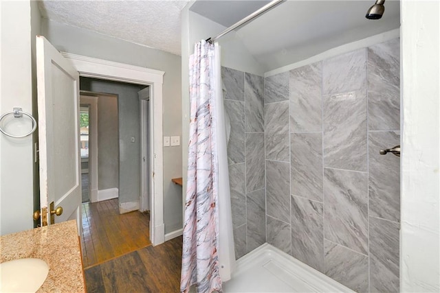 2409 Oakley Ave, Kansas City, MO 64127 - bathroom with hardwood / wood-style flooring, tiled shower, baseboards, a sink, and vaulted ceiling