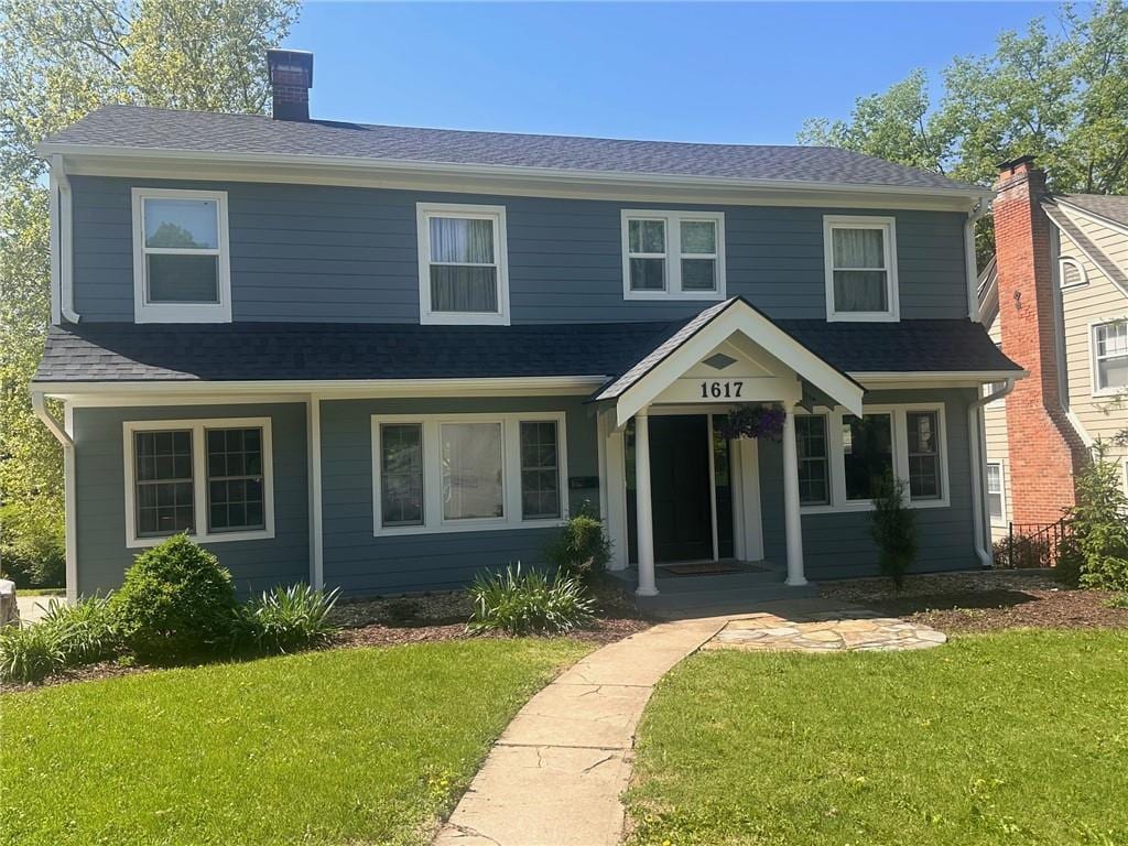 1617 W 50th St, Kansas City, MO 64112 - view of front of house with a front yard, a chimney, and roof with shingles