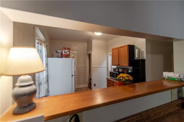 911 N 6th St, Atchison, KS 66002 - kitchen with freestanding refrigerator, brown cabinetry, stainless steel microwave, and baseboards