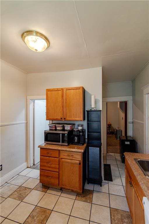 911 N 6th St, Atchison, KS 66002 - kitchen featuring stainless steel microwave, brown cabinetry, light tile patterned floors, and light countertops