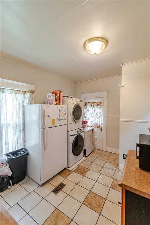 911 N 6th St, Atchison, KS 66002 - washroom featuring stacked washing machine and dryer, plenty of natural light, light tile patterned flooring, and ornamental molding