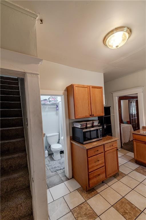 911 N 6th St, Atchison, KS 66002 - kitchen featuring stainless steel microwave, light tile patterned floors, and brown cabinets