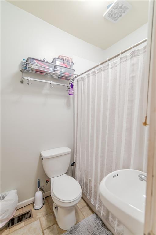 911 N 6th St, Atchison, KS 66002 - full bathroom featuring toilet, baseboards, a shower with shower curtain, and tile patterned flooring