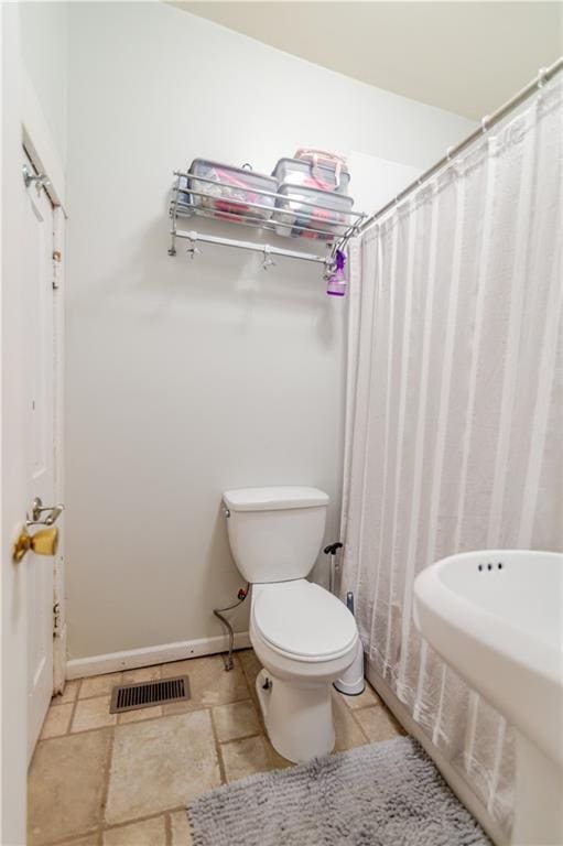 911 N 6th St, Atchison, KS 66002 - bathroom featuring a shower with curtain, toilet, baseboards, and stone finish floors