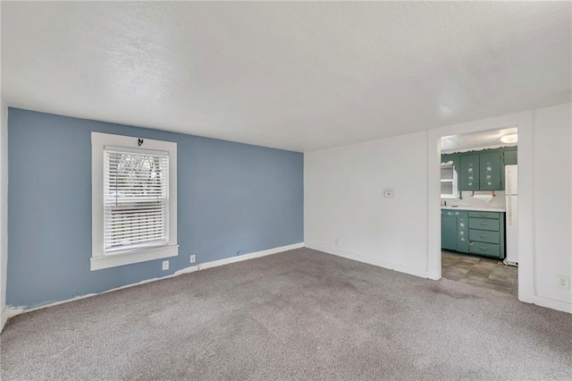 carpeted empty room featuring baseboards