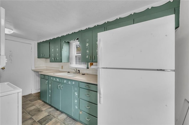 kitchen featuring freestanding refrigerator, green cabinetry, and light countertops