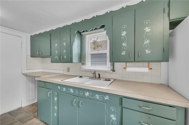 kitchen featuring tasteful backsplash, light countertops, a sink, and green cabinets