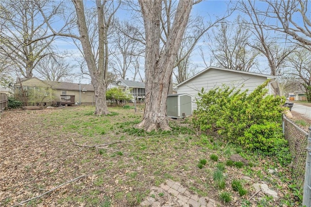 view of yard with a storage shed, an outdoor structure, fence, and a wooden deck