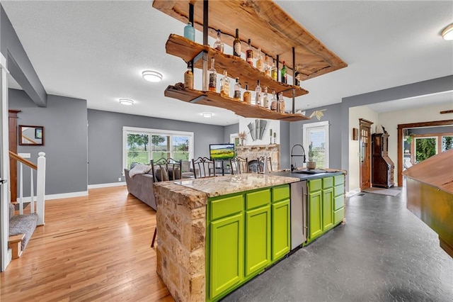 11261 238th St, Lawrence, KS 66044 - kitchen featuring green cabinetry, baseboards, a sink, a center island with sink, and a fireplace