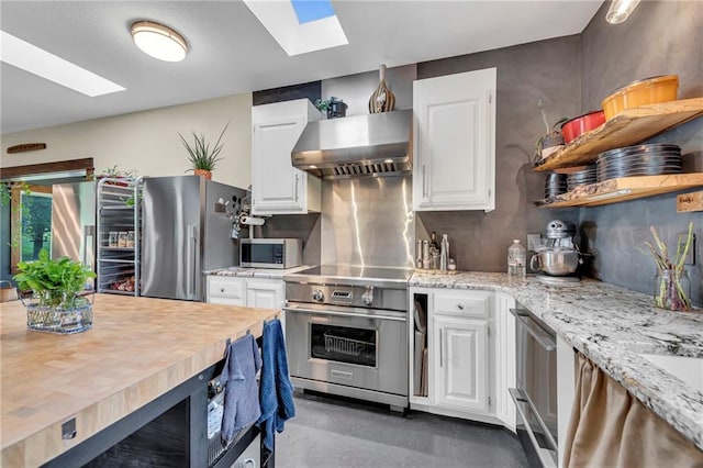 11261 238th St, Lawrence, KS 66044 - kitchen featuring a skylight, appliances with stainless steel finishes, range hood, and white cabinetry
