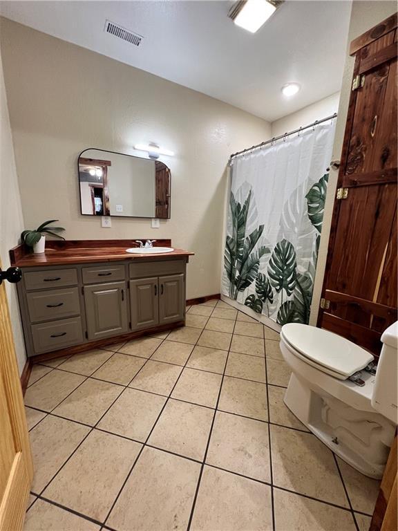 702 N Cedar St, Nevada, MO 64772 - full bathroom with vanity, tile patterned floors, and a shower with curtain