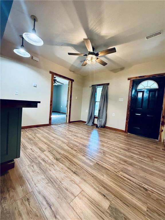 702 N Cedar St, Nevada, MO 64772 - unfurnished living room featuring ceiling fan and wood finished floors