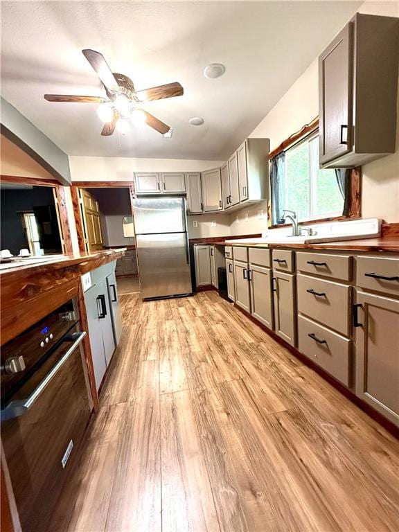 702 N Cedar St, Nevada, MO 64772 - kitchen featuring freestanding refrigerator, gray cabinets, light wood-type flooring, ceiling fan, and oven
