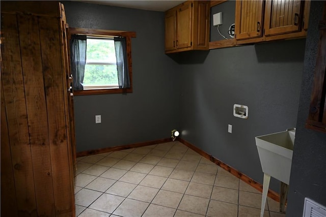 702 N Cedar St, Nevada, MO 64772 - laundry area featuring light tile patterned flooring, washer hookup, and cabinet space