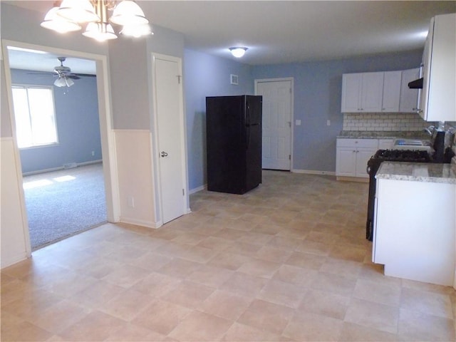 3020 N 81st St, Kansas City, KS 66109 - kitchen featuring freestanding refrigerator, a ceiling fan, white cabinetry, a chandelier, and decorative backsplash