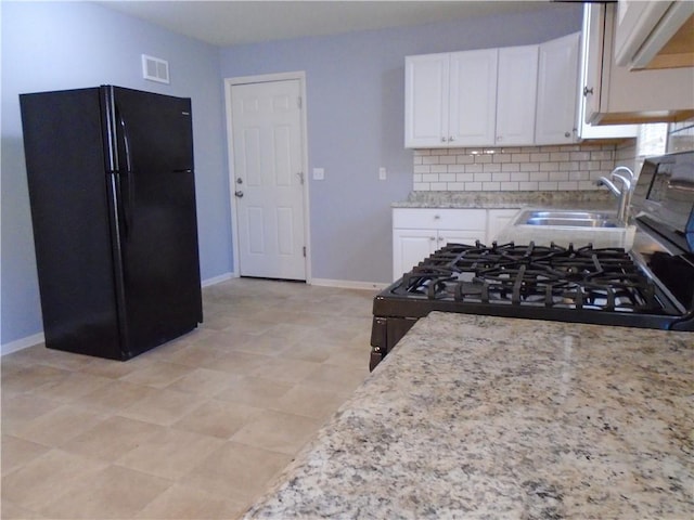 3020 N 81st St, Kansas City, KS 66109 - kitchen with freestanding refrigerator, a sink, white cabinetry, and baseboards