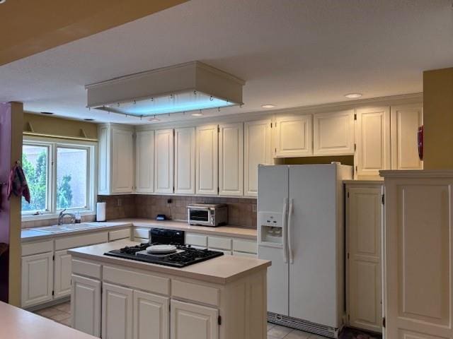 9803 W 121st St, Overland Park, KS 66213 - kitchen featuring white refrigerator with ice dispenser, light countertops, gas stovetop, white cabinetry, and a kitchen island