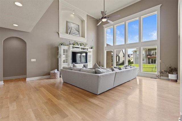 15825 Howe St, Overland Park, KS 66224 - living room with arched walkways, a high ceiling, ceiling fan, light wood-type flooring, and baseboards