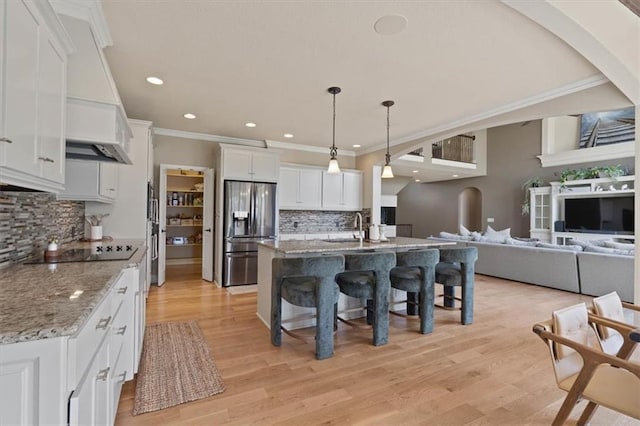 15825 Howe St, Overland Park, KS 66224 - kitchen featuring stainless steel fridge with ice dispenser, black electric cooktop, a kitchen bar, tasteful backsplash, and white cabinetry