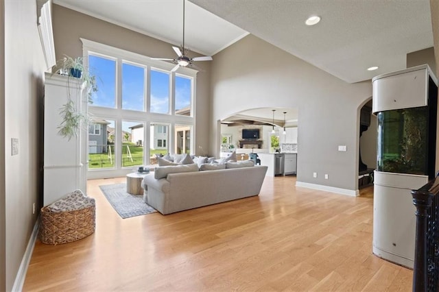 15825 Howe St, Overland Park, KS 66224 - living room with arched walkways, a ceiling fan, baseboards, high vaulted ceiling, and light wood finished floors