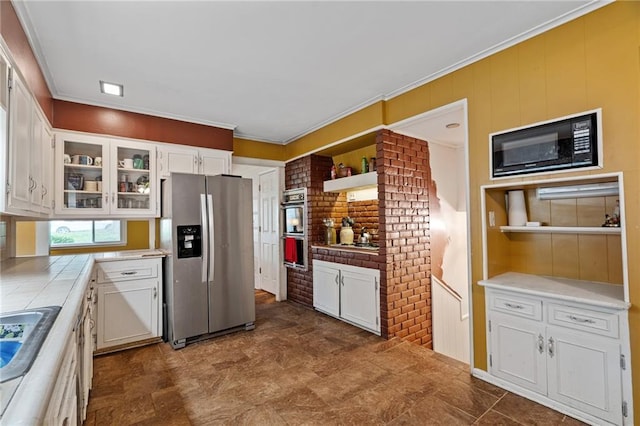 5347 Buena Vista St, Roeland Park, KS 66205 - kitchen with appliances with stainless steel finishes, tile countertops, white cabinets, glass insert cabinets, and ornamental molding
