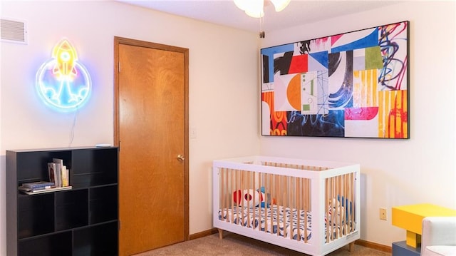bedroom with a nursery area, carpet, and baseboards