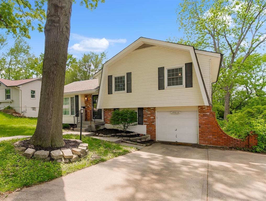 10632 Indiana Ave, Kansas City, MO 64137 - tri-level home with brick siding, a garage, and concrete driveway