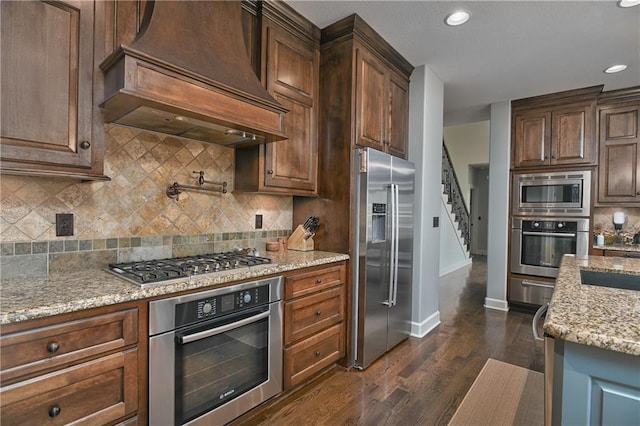 4502 Verona Ct, Riverside, MO 64150 - kitchen with stainless steel appliances, custom range hood, light stone countertops, baseboards, and dark wood-type flooring