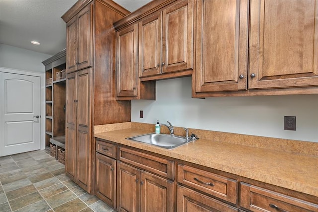 4502 Verona Ct, Riverside, MO 64150 - kitchen featuring a sink, light countertops, recessed lighting, stone finish floors, and brown cabinetry