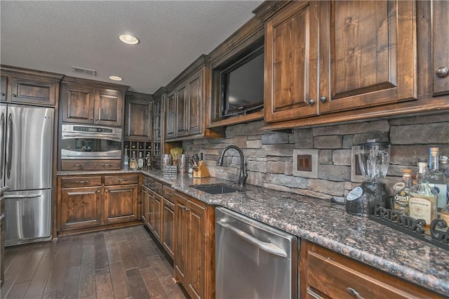 4502 Verona Ct, Riverside, MO 64150 - kitchen with stainless steel appliances, a sink, dark stone counters, a textured ceiling, and dark wood-type flooring