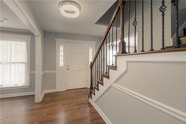 foyer with stairs, wood finished floors, and baseboards