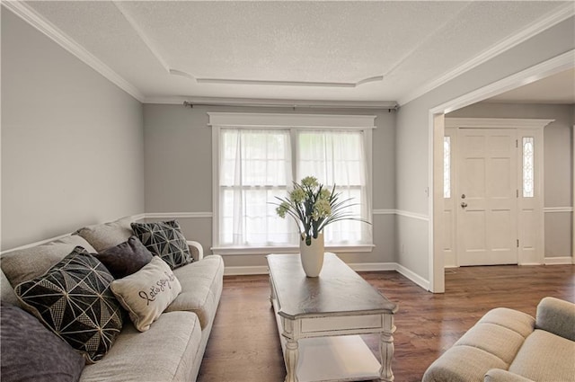 living room featuring a textured ceiling, wood finished floors, ornamental molding, and baseboards
