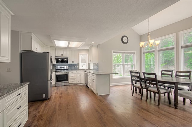 kitchen featuring stainless steel appliances, dark wood-style floors, a chandelier, a peninsula, and a sink