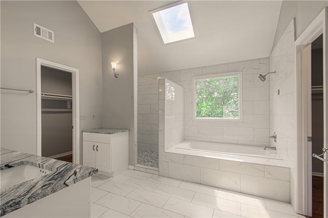 bathroom with vaulted ceiling, a skylight, vanity, a spacious closet, and marble finish floors