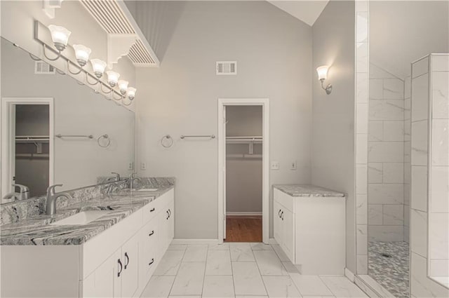full bath featuring marble finish floors, double vanity, a spacious closet, a walk in shower, and high vaulted ceiling