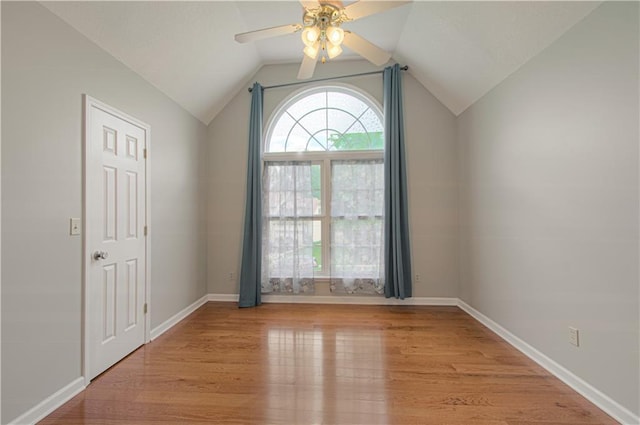 empty room featuring light wood-style flooring, ceiling fan, vaulted ceiling, and baseboards