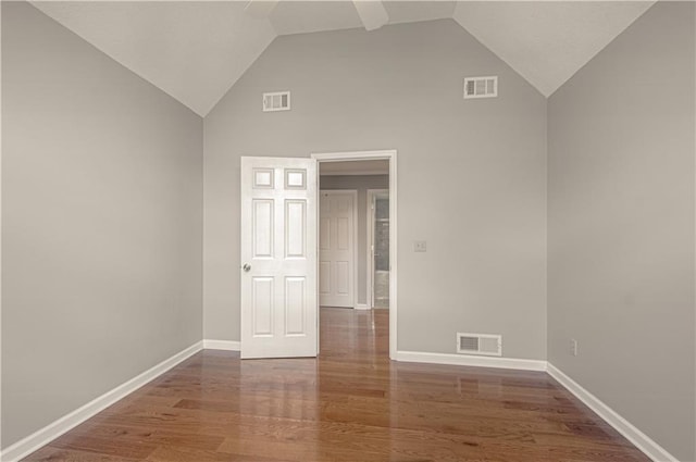 spare room featuring wood finished floors, baseboards, and high vaulted ceiling