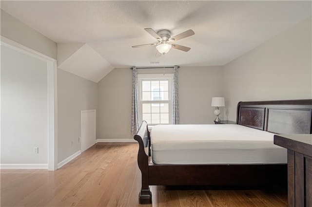 bedroom featuring light wood-type flooring, baseboards, a ceiling fan, and lofted ceiling
