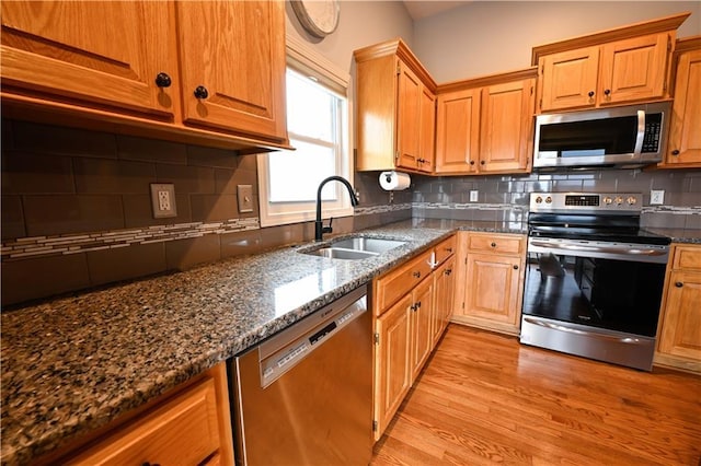 15363 S Darnell St, Olathe, KS 66062 - kitchen with appliances with stainless steel finishes, a sink, light wood-type flooring, backsplash, and dark stone counters