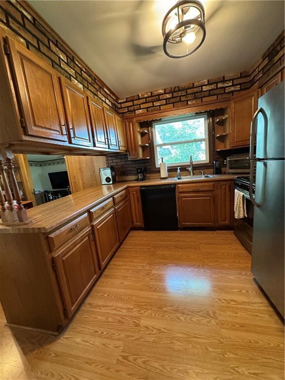 209 S 4th St, Arma, KS 66712 - kitchen featuring stainless steel appliances, open shelves, a sink, brown cabinetry, and light wood finished floors