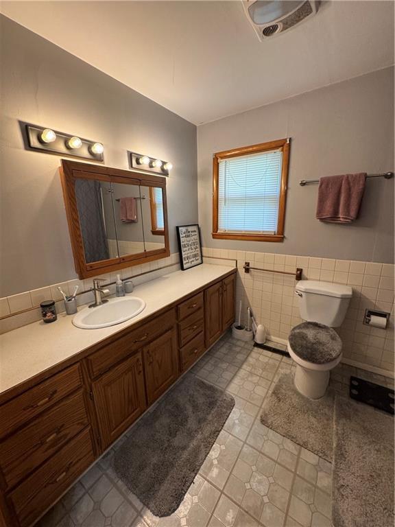 209 S 4th St, Arma, KS 66712 - bathroom featuring tile walls, toilet, vanity, and wainscoting