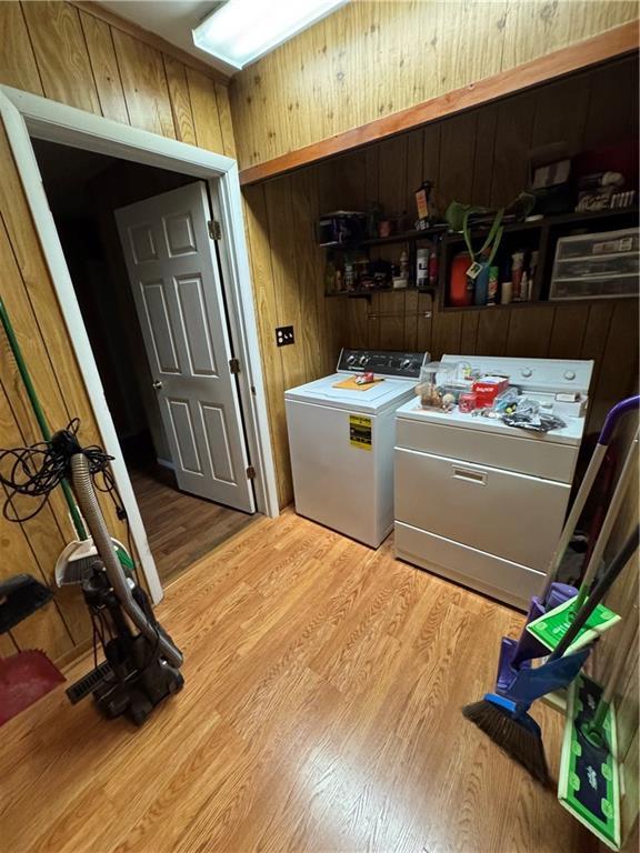 209 S 4th St, Arma, KS 66712 - clothes washing area with washer and dryer, light wood-style floors, and wood walls