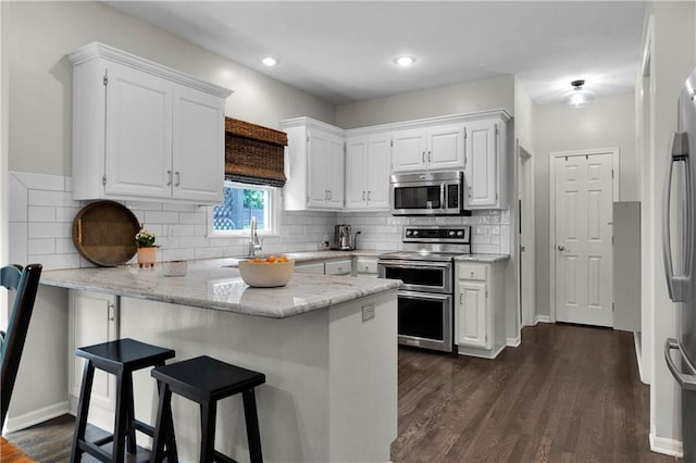 5318 W 159th Ter, Overland Park, KS 66085 - kitchen with stainless steel appliances, a peninsula, white cabinets, a breakfast bar area, and recessed lighting