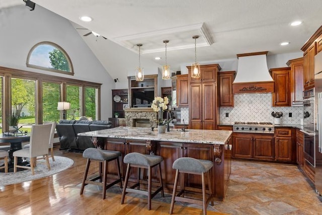 8127 Lone Elm Rd, Lenexa, KS 66220 - kitchen featuring wall chimney range hood, stainless steel appliances, light stone counters, a breakfast bar, and backsplash
