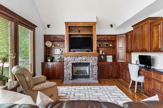 8127 Lone Elm Rd, Lenexa, KS 66220 - living room featuring lofted ceiling, wood finished floors, and a stone fireplace