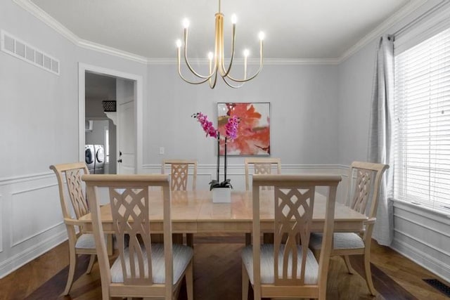 8127 Lone Elm Rd, Lenexa, KS 66220 - dining space with separate washer and dryer, a chandelier, ornamental molding, a decorative wall, and wood finished floors